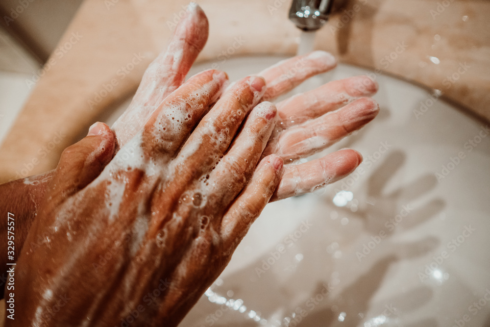 Middle-aged woman washing her hands with soap and water to avoid contagion of the coronavirus. Health risk prevention. Healthcare