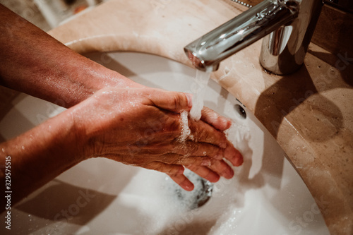 Middle-aged woman washing her hands with soap and water to avoid contagion of the coronavirus. Health risk prevention. Healthcare