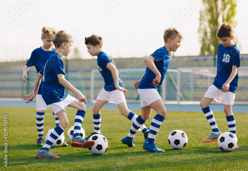 Kids Sports: Teaching Children to Improve Soccer Skills. Football camp for kids. Boys practice dribbling in field. Players develop skills. Children training with balls. Soccer slalom drills