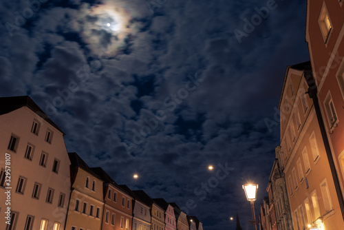 Old merchant houses in Regensburg during night with full moon and clouds