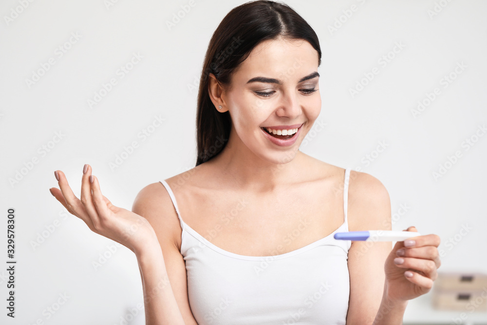 Happy young woman with pregnancy test in bathroom Happy young woman with pregnancy test in bathroom