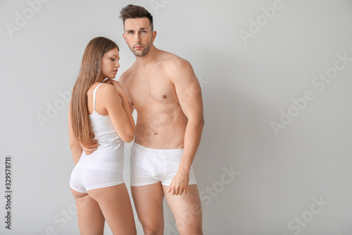Young couple in underwear on light background
