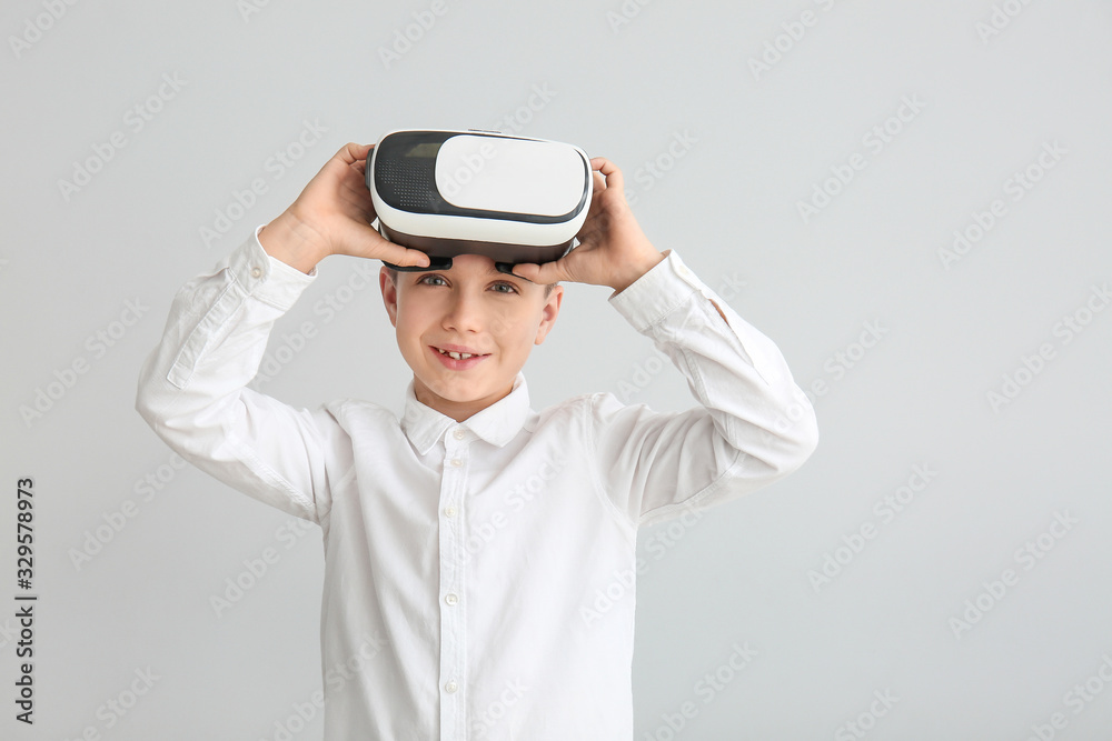 Little boy with virtual reality glasses on grey background Little boy with virtual reality glasses on grey background