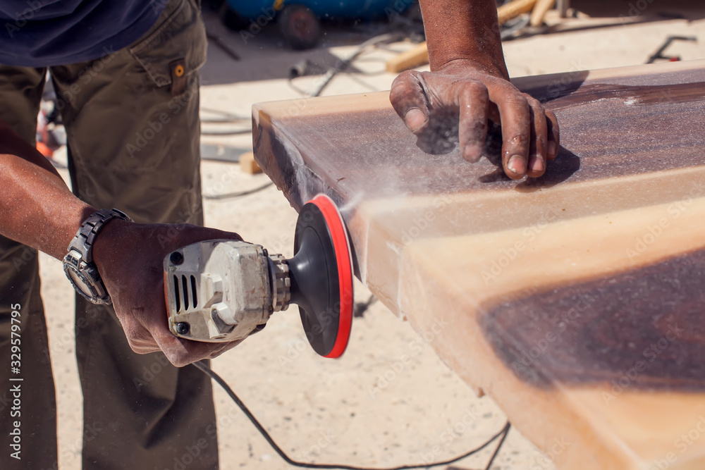 A handyman grinding wooden plank outdoor. A handyman grinding wooden plank outdoor.
