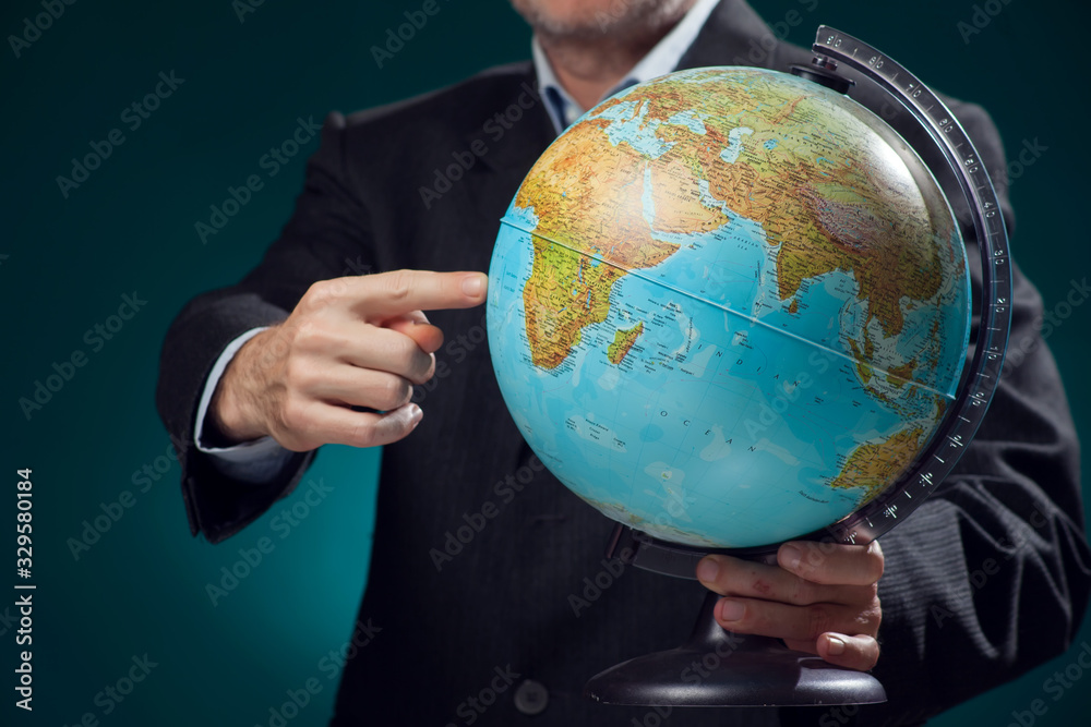 A man in suit holding globe and pointing with finger at it. Business, education and idea concept A man in suit holding globe and pointing with finger at it. Business, education and idea concept