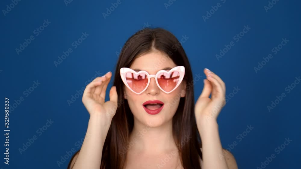 Portrait of a beautiful girl in pink glasses on a blue background