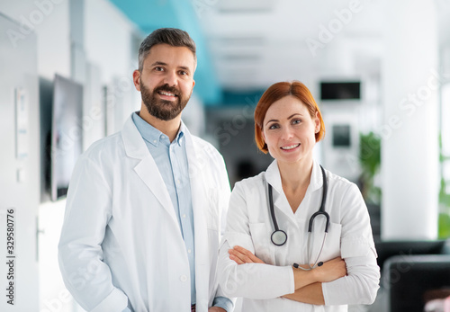 A portrait of man and woman doctor standing in hospital.