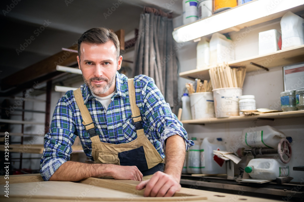 Smiling and proud mature carpenter in his carpentry workshop Smiling and proud mature carpenter in his carpentry workshop