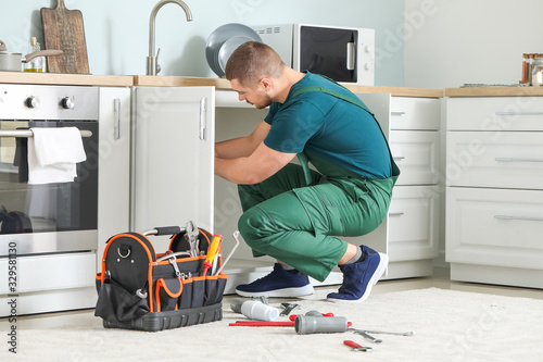 Handsome plumber repairing ...
