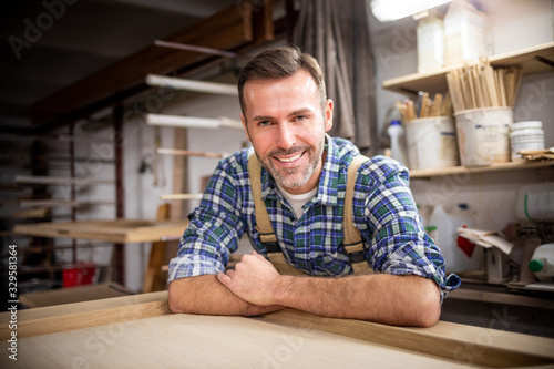Smiling and proud mature carpenter in his carpentry workshop
