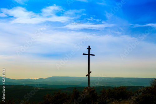 Black religion symbol silhouette Jesus Christ wooden cross on a background with colorful mountain sunset, Easter concept.