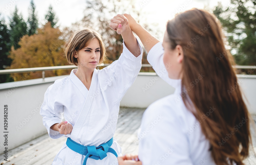 Obraz premium Young women practising karate outdoors on terrace.