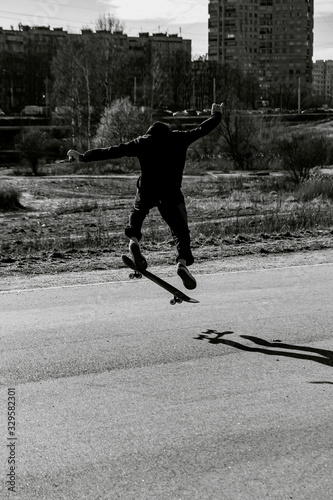 Teenager man on skateboard practicing at the park making jump and perform stunts  in spring autumn in motion in black and white picture. Sport extreme concept