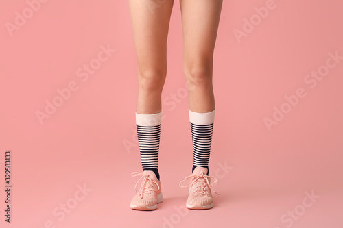 Legs of young woman in socks and shoes on color background