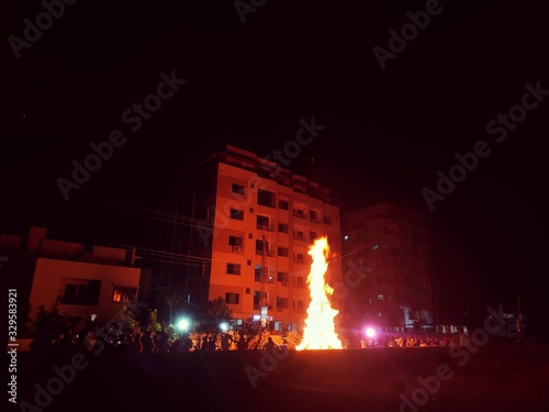 Huge bonfire burning wood and grass fire ignite to celebrate holi festival. Focus on fire. photo