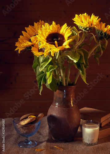 Bouquet of sunflowers in a clay jug on the table on the wooden background.