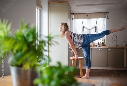 Young woman relaxing indoors at home, stretching.