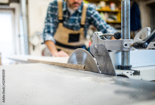 Close up of circular saw cutting wooden board in carpentry workshop