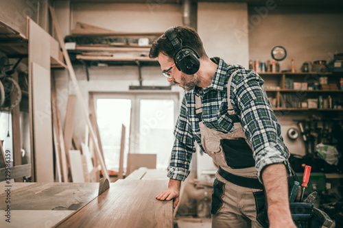 Circular saw cutting a wooden board in carpentry workshop
