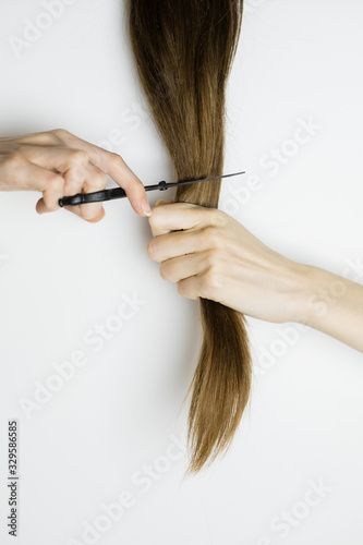 Close up - Unrecognizable upset woman cuts her long straight hair with scissors. Copy space.