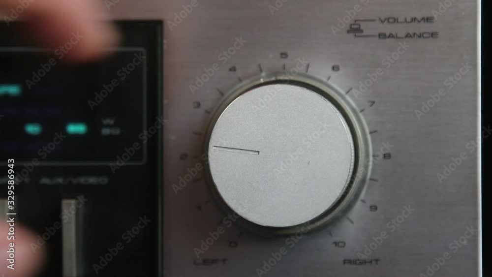 Close up of hand turning a volume knob on home stereo unit
