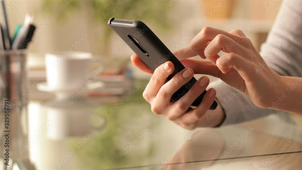 Close up of a woman hands using smart phone on a desk at home