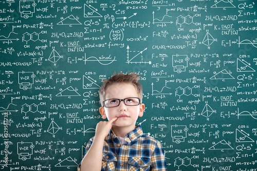 Student boy on blackboard background with formulas