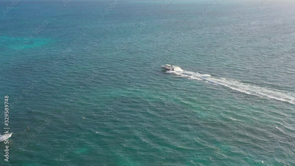 Aerial, pan, drone shot following a boat driving on the Caribbean ocean, on the coast of Caye Caulker island, sunny day, in Belize, Central America Aerial, pan, drone shot following a boat driving on the Caribbean ocean, on the coast of Caye Caulker island, sunny day, in Belize, Central America