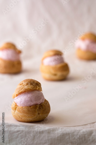 Homemade choux cream or cream puffs with strawberry cream on white background.