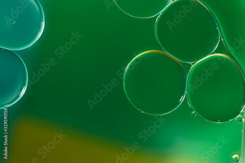 Close up ,oil drops floating on water surface ,With green background