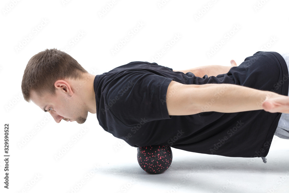 A man makes strengthening exercises for the body with special sports equipment. Self massage increases the body's tone A man makes strengthening exercises for the body with special sports equipment. Self massage increases the body's tone