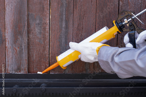 Fotografía Technician man hand holding glue gun with silicone adhesive or manual caulking gun with polyurethane to repair and fix the metal steel to wood material