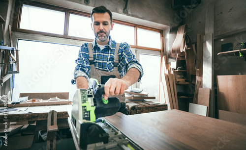 Carpenter using professional circular saw to cutting a wooden board in carpen...