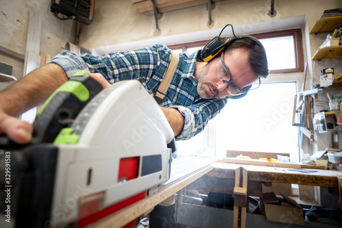 Carpenter using professional circular saw to cutting a wooden board in carpen...