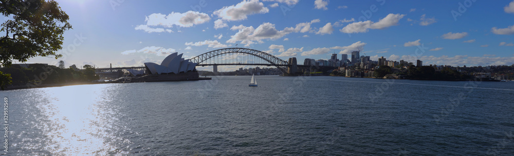 Fototapeta premium Panorama of Sydney Harbour bridge on a warm summer afternoon at Sunset blue skies and white orange clouds