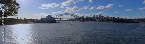 Panorama of Sydney Harbour bridge on a warm summer afternoon at Sunset blue skies and white orange clouds © Elias Bitar