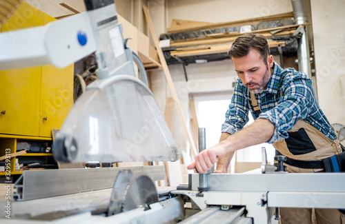 Carpenter preparing circular saw to work at carpentry workshop