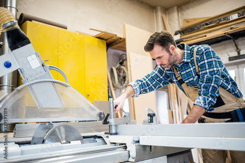 Carpenter preparing circular saw to work at carpentry workshop