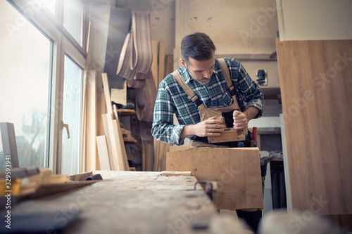 Carpenter planing a wooden board with a manual planer in carpentry workshop