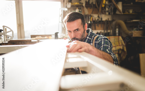 Carpenter checking if the wooden board is flat and even