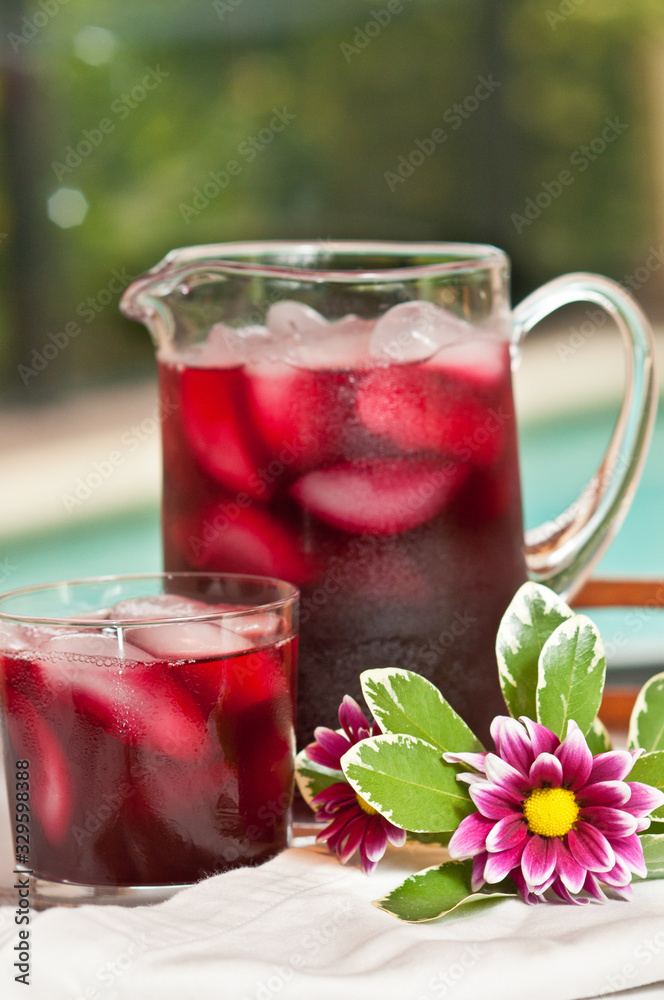 Front view, close distance of a glass pitcher and two glasses of raspberry punch, served at pool side of a luxury hotel Front view, close distance of a glass pitcher and two glasses of raspberry punch, served at pool side of a luxury hotel
