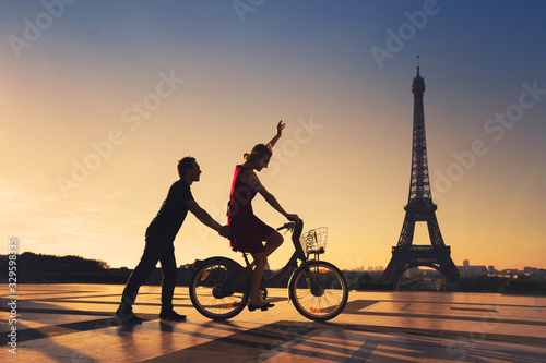 Photography happy couple having fun in Paris riding bicycle near Eiffel tower, silhouettes
