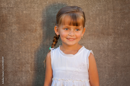 Closeup portrait of a pretty little girl in white dress 