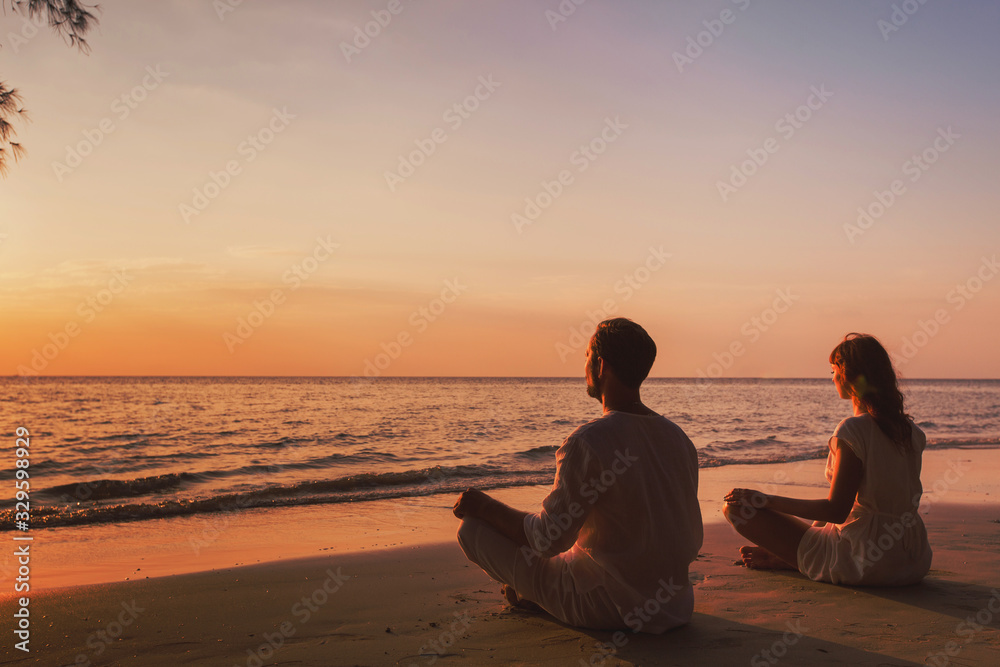 meditation and relaxation for couple, yoga group on the beach at sunset