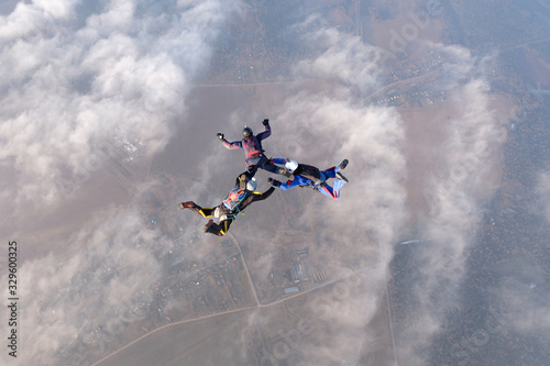 Skydiving. Three skydivers are in the sky above white clouds.