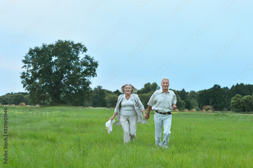 Happy beautiful senior couple running in summer field Happy beautiful senior couple running in summer field