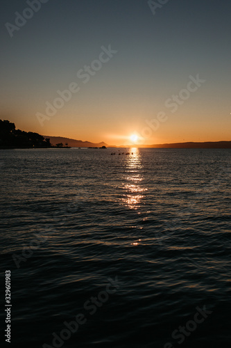 photo of young European Muslim women with hijab standing and looking into distance. Sea is in the background. She is happy and relaxed. Photos taken during sunrise.  