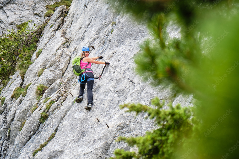 Woman tourist on a traverse at Intersport Klettersteig Donnerkogel via ferrata route, near Gosau, in Austria.