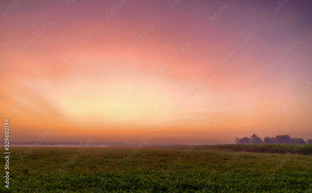 Colorful glowing sunrise over a countryside farming area, creating an idyllic scenic landscape