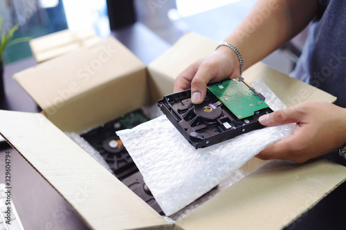 hand of business man holding Harddisk for PC and Bubble Wrap or Bubble sheet for Wrapping near parcel box on black desk in home office .selective focus photo